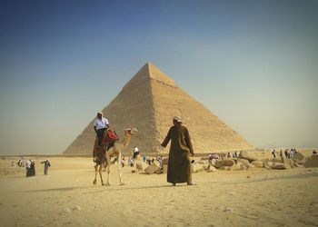 Tourist sitting on camel against pyramid