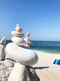 Pebbles on beach against clear sky
