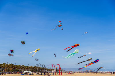 Low angle view of kites flying against clear blue sky