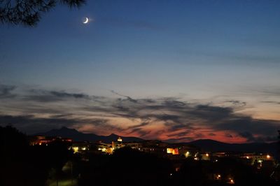 Illuminated town against sky at night