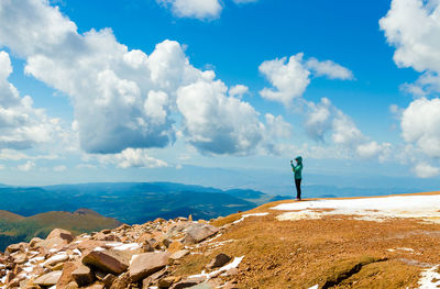 Woman on mountain peak against sky