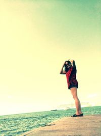 Woman standing on beach against clear sky