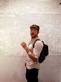 Portrait of young man standing against wall