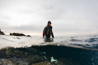 Male swimmer standing waist deep in sea water