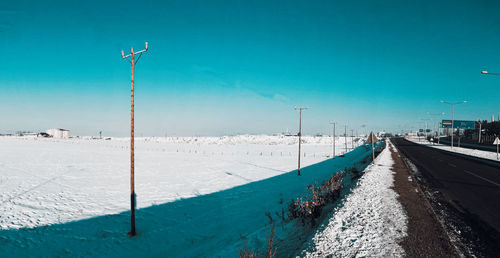 Snow covered road against clear blue sky