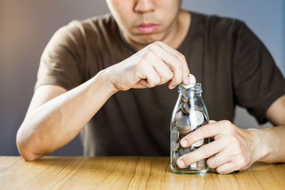 Midsection of man holding bottle on table