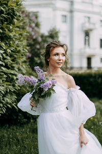 A beautiful delicate elegant young woman bride in a wedding dress walks in a blooming spring park