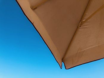 Low angle view of parasol against clear blue sky