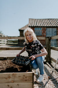 Portrait of smiling woman holding crate