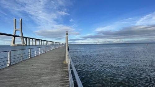 Bridge over calm sea against sky