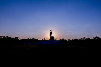 Silhouette statue against sky at sunset