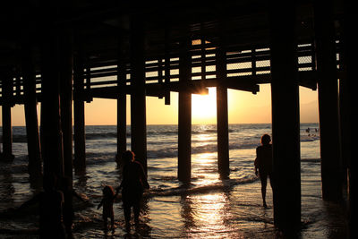 Silhouette pier on beach against sky during sunset