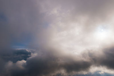 Low angle view of sunlight streaming through clouds