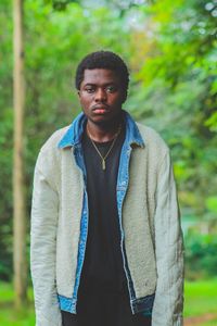 Portrait of young man standing against trees