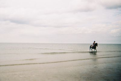 Rear view of men walking on beach against sky