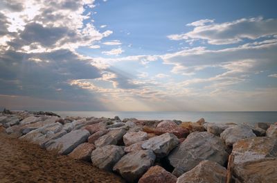 Rocks on sea shore against sky during sunset