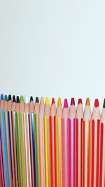 Close-up of colored pencils arranged over white background