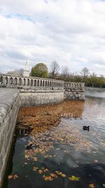 View of dam on river against cloudy sky