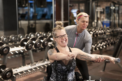 Woman on wheelchair training in gym with personal trainer