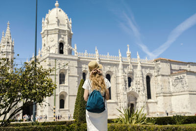 Woman standing by historic building against sky