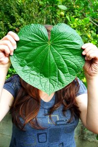 Close-up of girl with hand holding leaf