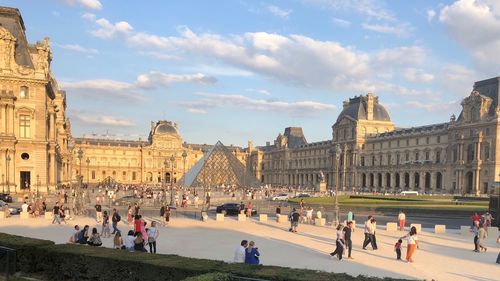 People at historic place against cloudy sky