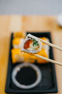 Close-up of sushi in chopsticks in plate