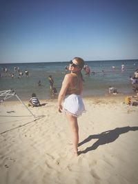 Young woman wearing bikini while standing on sand at beach