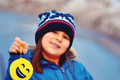 Portrait of smiling cute girl holding emoticon