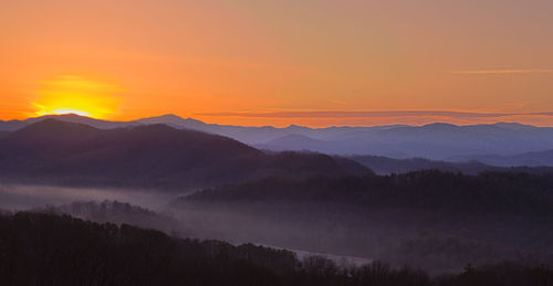 Scenic view of silhouette mountains against orange sky