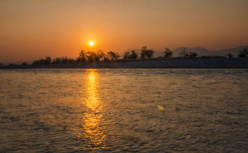 Scenic view of lake against orange sky