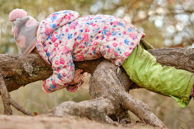 Side view of girl lying on tree