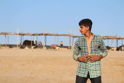 Man standing on beach against clear sky