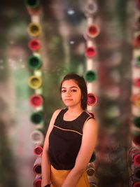 Portrait of young woman standing against wall