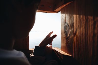 Rear view of man working on wooden window