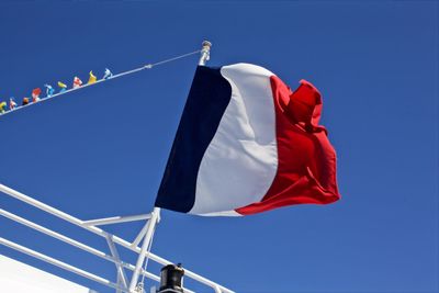 Low angle view of flag against clear blue sky