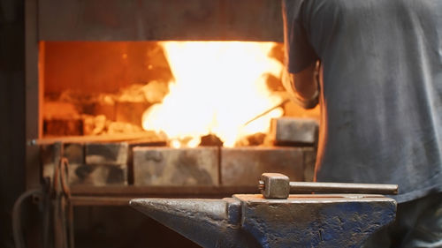 Midsection of man standing by fire in workshop