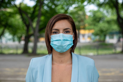 Portrait of young woman wearing mask standing outdoors