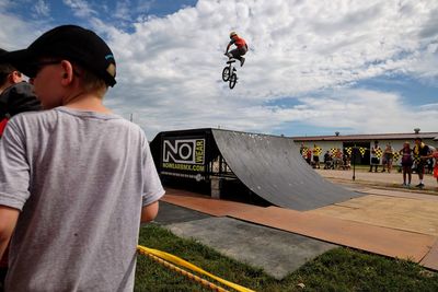 Rear view of man skateboarding on skateboard against sky