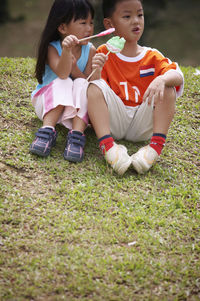 Friends holding candies while sitting on field at park