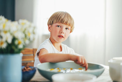 Portrait of boy sitting by table at home