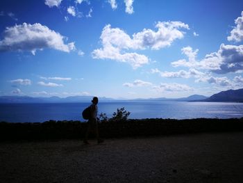 Silhouette man standing by sea against blue sky