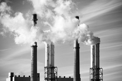 Low angle view of smoke emitting from stacks against sky