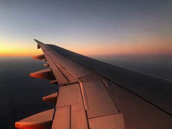 Airplane flying over sea against sky during sunset