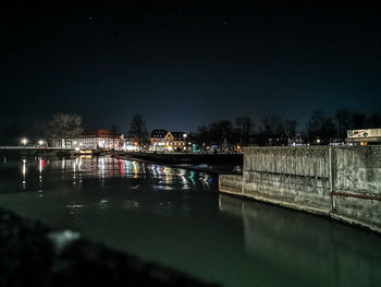 Illuminated bridge over river against sky at night