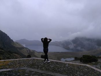 Rear view of man standing on mountain against sky