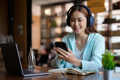 Young woman using mobile phone while sitting at cafe