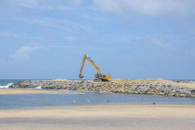 Construction site by sea against sky