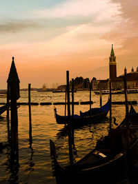 Boats moored in canal at sunset