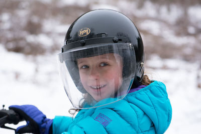 Portrait of girl wearing crash helmet on snow covered field